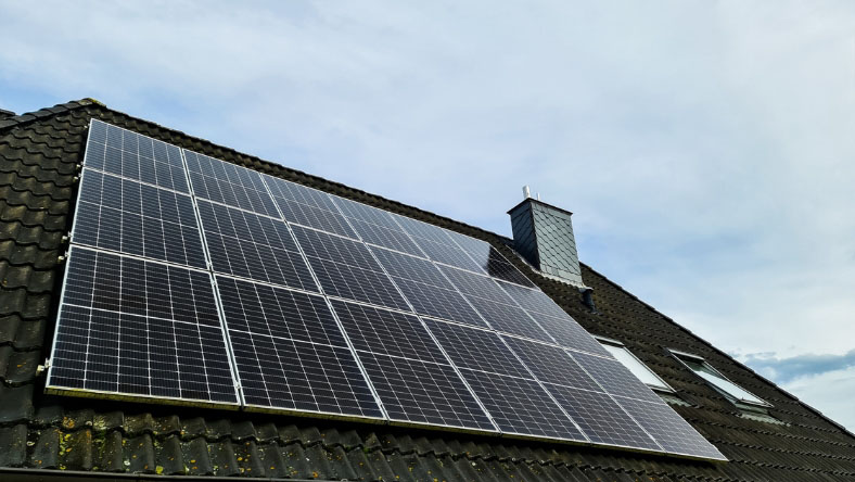 Solar panels installed on the roof of a house under a clear sky.