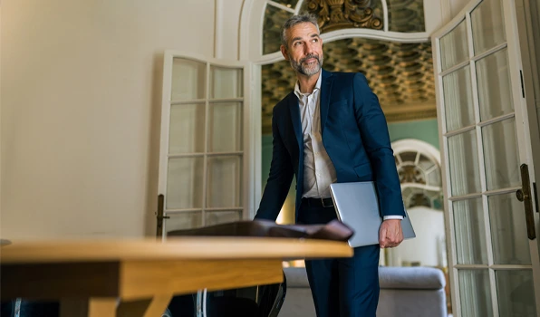 Professional carrying a laptop while entering an office building, illustrating the exclusive banking, financial planning, and lifestyle benefits available through Club Five.
