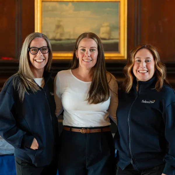 Three Salem Five employees posing together indoors in front of a framed painting in an office setting.