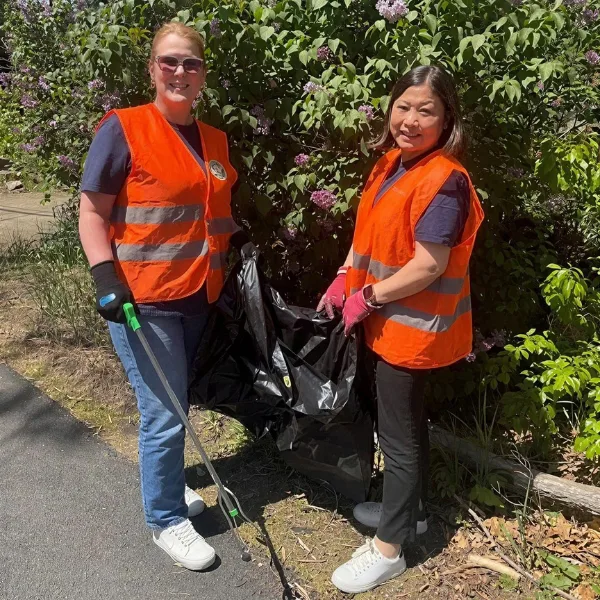 Salem Five employees volunteering outdoors wearing safety vests and collecting trash during a community cleanup event.