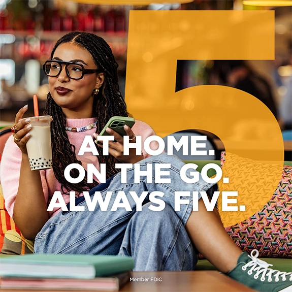 Person sitting in a lounge holding a drink and a phone with the text &ldquo;At Home. On the Go. Always Five.&rdquo;