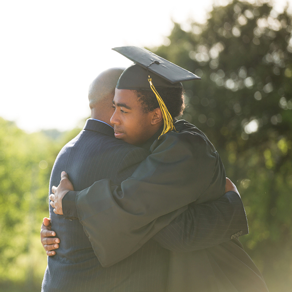 Graduate hugging parent.