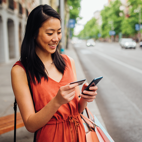 Smiling woman holding credit card and mobile phone